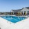 Kansas City, KS, Pet-Friendly Apartments - Switch - Rectangular Swimming Pool Surrounded by Sun Loungers, Patio Umbrellas, and View of Apartment Buildings.